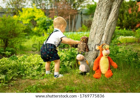 
A little boy steps to his soft toys in the garden.