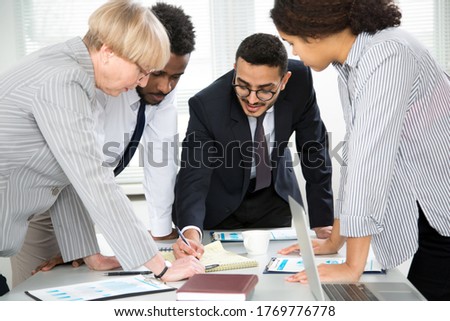 International group of business people working and communicating sitting near office desk together.
