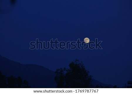 There is a picture of the moon on the mountain in blue tone.
