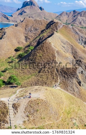 Scenic view from the top of Padar Island. Tourists enjoying the Savanna hill and taking pictures.