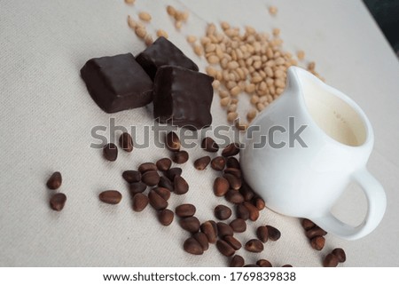 White ceramic milk jug with fresh milk. Chocolates, cinnamon and nuts