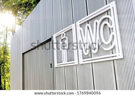 public toilet building against forest background. Front closeup view of modern restroom. Facade of outdoor lavatory with men WC sign