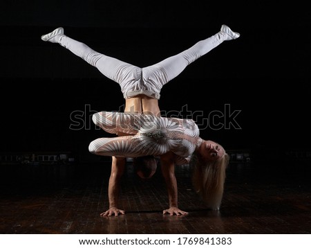 A sports couple of acrobats performs the trick. Acrobats on a dark background.