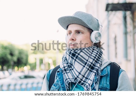 Caucasian man in headphones listens to music and walks around the city.