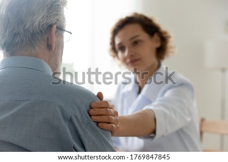 Close up of caring young Caucasian female nurse or caregiver touch support senior male patient, attentive woman doctor or GP feel supportive comfort upset mature man client, elderly healthcare concept Royalty-Free Stock Photo #1769847845