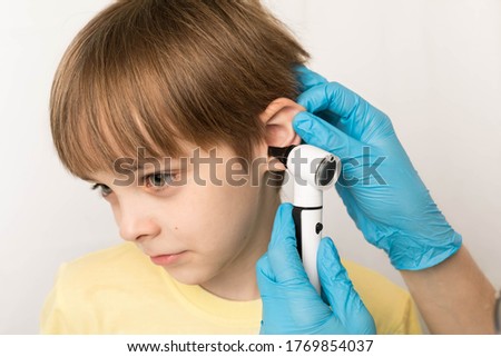 Pediatrician examines child's ears with an othscope in clinic