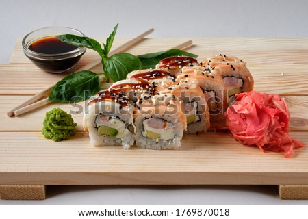 Japanese sushi rolls named Salmon roll with avocado, bacon, Crab meat, wasabi, soy sauce, nori and marinated ginger. Tasty and artistic food for restaurant or cafe menu. Roll on wooden board. Catalog