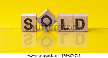 word sold is made of wooden building blocks lying on the table and on a light yellow background. Concept