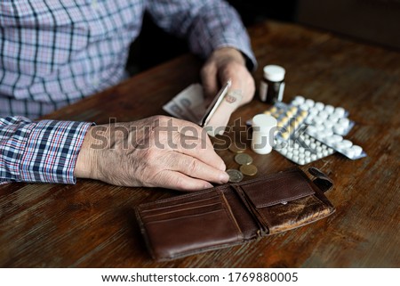 Hands of an old man counting money for medicine. Poverty, disease, low income in old age. Royalty-Free Stock Photo #1769880005