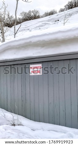 Vertical crop Gray wooden wall with Reserved Parking sign against snowy hill and sky in winter