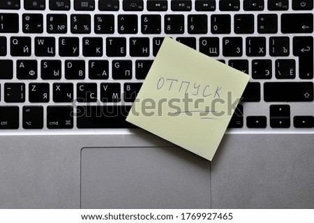 The inscription "vacation" in Russian, on a sticker on the background of a computer keyboard