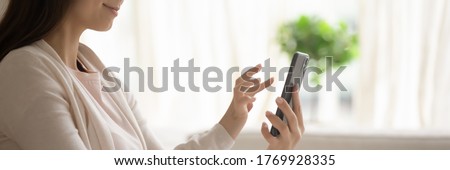 Satisfied young woman holding smartphone, browsing mobile device app close up cropped wide image, beautiful girl using phone, writing message in social network, shopping online, playing game