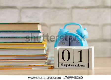 Back to school, September 1 on the calendar. Alarm clock and a stack of textbooks on the table