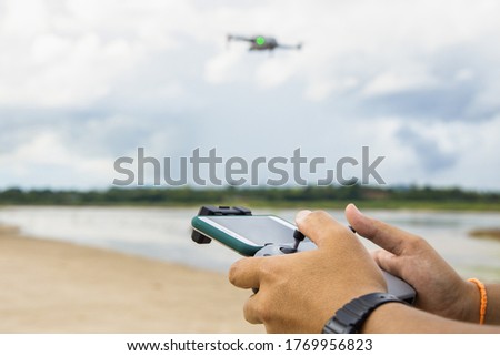 Man operating a drone with remote control. Drone with high resolution digital camera on the river and sky.
