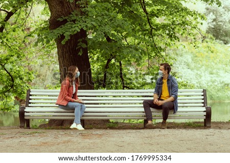 Young, happy, loving couple having date in the park during the coronavirus lockdown crisis. Relations, friendship and love concept. Social distancing and virus protection. Royalty-Free Stock Photo #1769995334