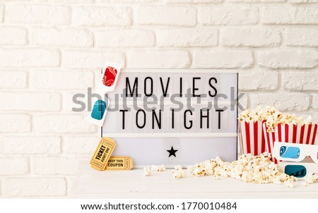 Lightbox with the words Movies Tonight, popcorn, 3d glasses and movie tickets front view with copy space