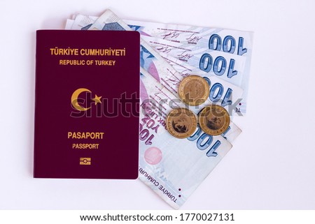 Turkish common passport on the white surface with some Turkish banknotes.