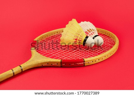 Shuttlecock on a badminton racket on a bright red background