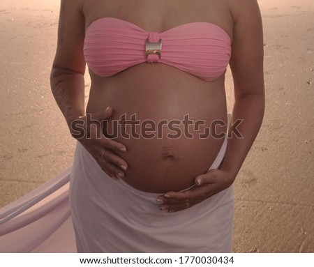 pregnant young woman on the beach with the sun rising