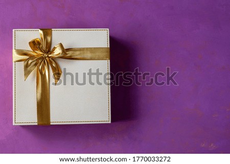 Gift with bow and daisy flowers on a pink background. Copy space.