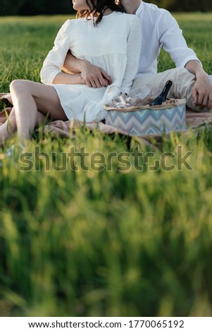 Faceless man and woman in white clothes having picnic on the nature. Love story. High quality photo
