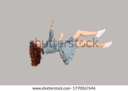 Floating in air. Relaxed girl in vintage ruffle dress levitating keeping eyes closed, sleeping while flying mid-air, having comfortable peaceful dream. full length studio shot isolated on gray, indoor