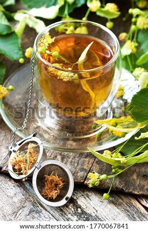Cup of herbal tea with linden flowers on  old wooden table.  Аlternative medicine сoncept