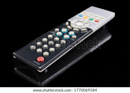 TV remote on a dark table. Electronic accessories in the household. Black background.