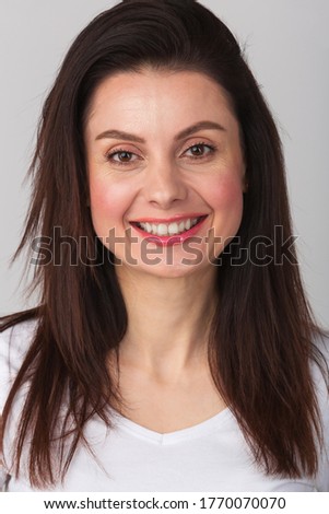 Happy young woman photo,toothy smile.Beautiful girl in 30s photo with white teeth,red lipstick in studio wearing casual white t-shirt.Download royalty free curated images with beautiful natural people