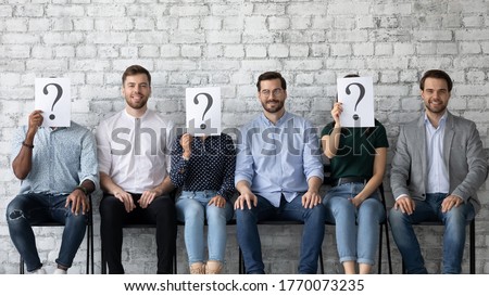 Three qualified men applicants interviewed successfully getting hired in company position concept. Six multi racial jobless people sit in line three of them hiding face behind paper with question mark