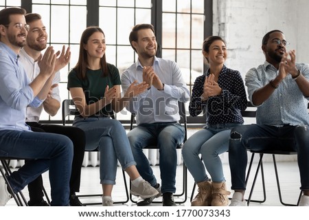 Group of cheerful employees sitting on chairs in boardroom clap hands encourage business coach start workshop. Six participants express gratitude applauding to trainer after seminar activity concept Royalty-Free Stock Photo #1770073343