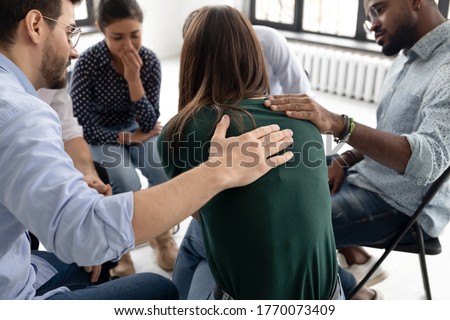 Multi ethnic people gathered together sitting on chairs in circle supporting crying desperate girl during group therapy session, medical detox center, psychological help assistance at meeting concept Royalty-Free Stock Photo #1770073409