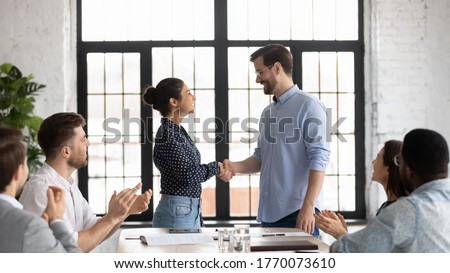 Indian and caucasian business people shake hands start negotiations with partners at boardroom. Staff cheering best employee of month receive praises, gratitude from boss, worker get promotion concept Royalty-Free Stock Photo #1770073610