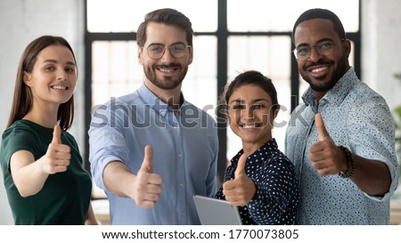 Proud multi ethnic business team young people showing thumbs up looking at camera. Smiling professional corporate staff group diverse happy four employees photo shoot. Human resource, advance concept