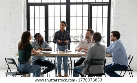 Indian business trainer teach multi-ethnic members during training seminar activity, coach stand in front of staff speaking about corporate goals, methods to succeed them. Negotiations meeting concept Royalty-Free Stock Photo #1770073853