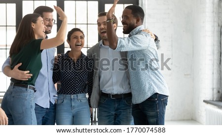 Five multi ethnic students or company employees accomplish project, exam pass, embracing feels excited celebrating common success giving high 5, gesture of unity racial equality and friendship concept Royalty-Free Stock Photo #1770074588
