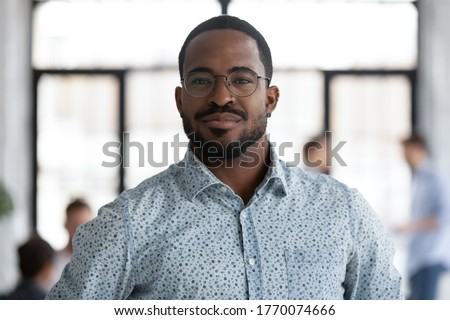 Head shot of african self-assured executive manager portrait, successful staff member company employee pose for camera photo shooting standing in office. Firm owner, proud founder, leadership concept Royalty-Free Stock Photo #1770074666