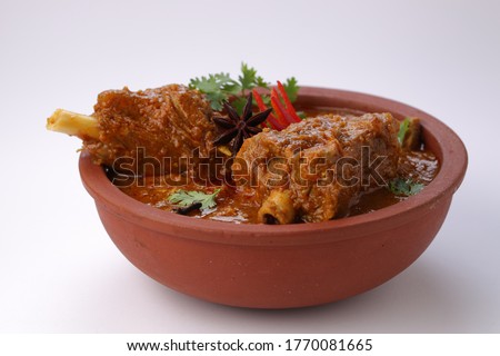 Mutton curry or Lamb curry,spicy and delicious dish garnished with coriander leaf ,red chilli  and star anise  spice in an earthenware bowl with white background. Royalty-Free Stock Photo #1770081665