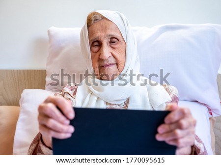 Portrait of senior Arabic woman using electronic tablet at home