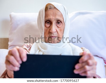 Portrait of senior Arabic woman using electronic tablet at home
