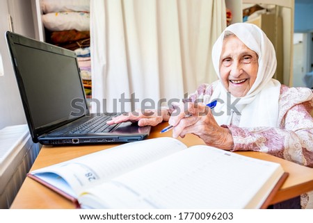 Old women studying and writing using laptop and notebook