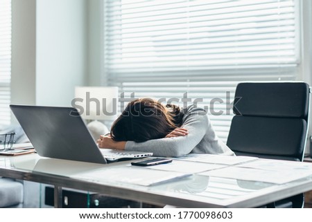 Young woman in office at her workplace is tired and resting