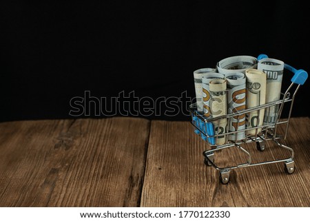 Shopping cart and Euro banknotes. Dollars