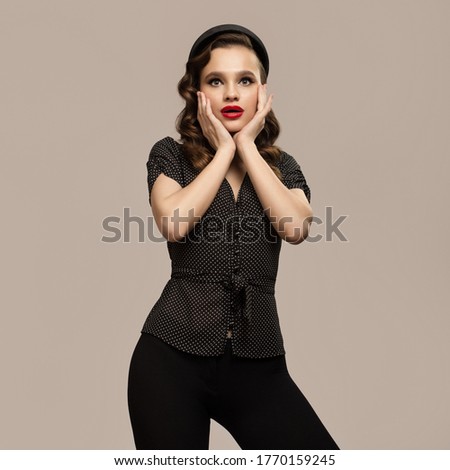 Portrait of beautiful surprised pin-up girl on gray background. Retro fashion.