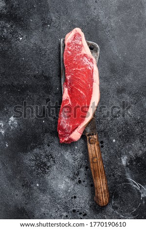 Raw sirloin steak on a cleaver. Marble beef. Black background. Top view