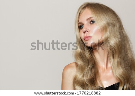 portrait of a blonde woman with wavy hair. gray copycpase background