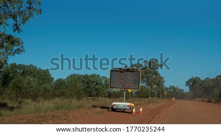 Traffic signals ahead reduce speed sign on unsealed dirt road in the Australian outback