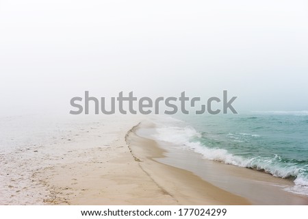 Soft pastel landscape photo of waves breaking on a pristine, peaceful, unpopulated beach.