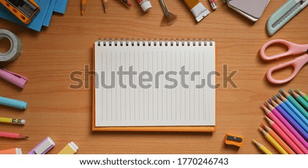 Top view image of the student desk is surrounding by an empty notebook and stationary.