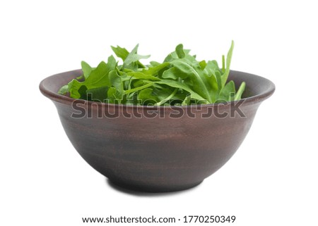 Fresh leaves of arugula in ceramic brown bowl isolated on white background. 
